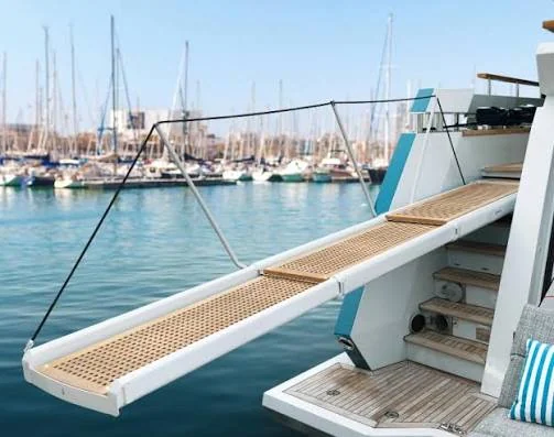 White and teak yacht passerelle extended over a marina dock