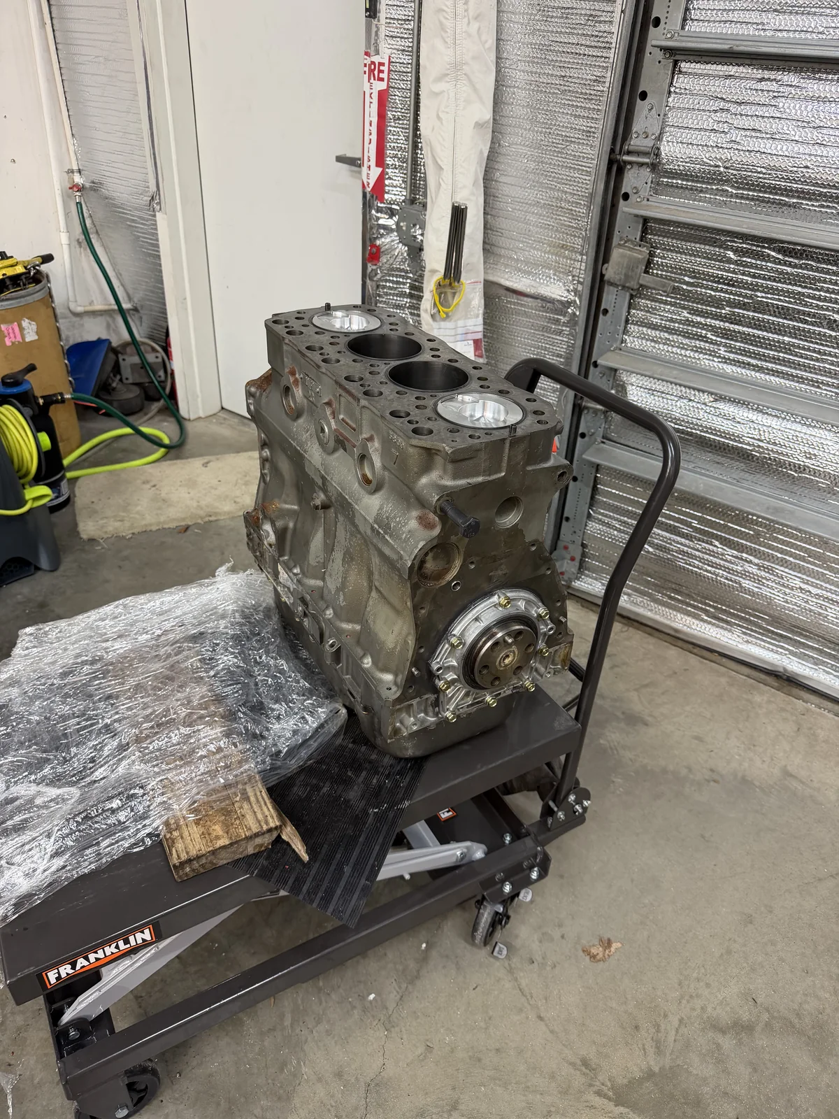 Open four-cylinder engine block positioned on a hydraulic lift table.